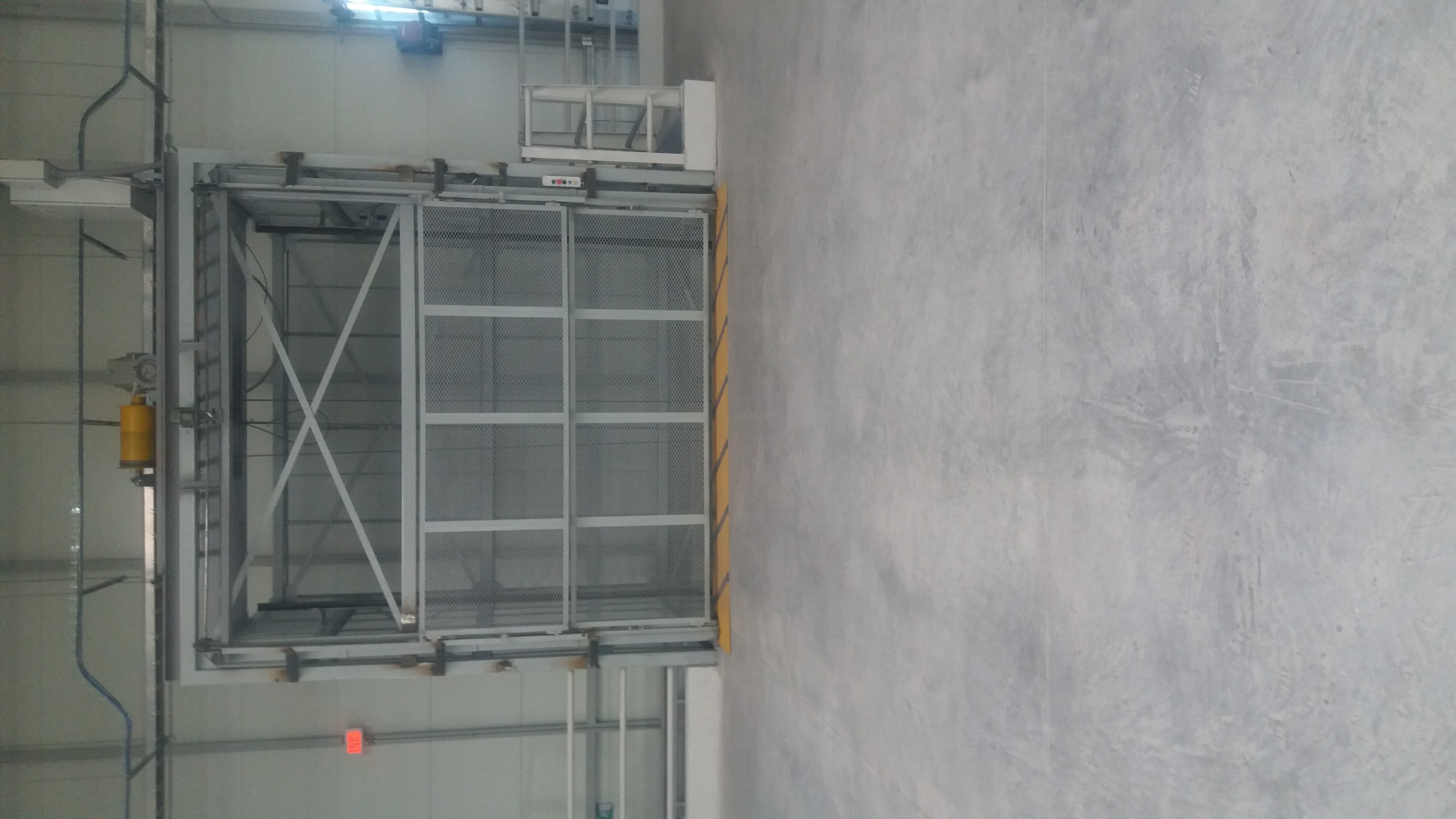 Elevador de carga EPCCSA con máquina de tracción superior y puerta de malla instalado en planta industrial