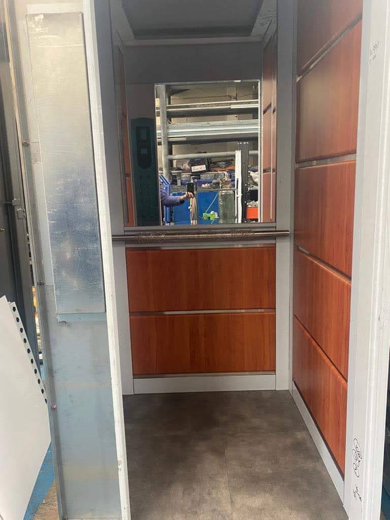 Interior de cabina de elevador residencial EPCCSA con paneles de madera, espejo y pasamanos