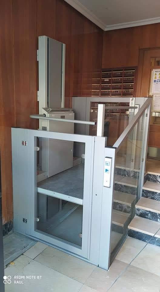 Plataforma elevadora EPCCSA con puerta de cristal instalada en portal de edificio residencial