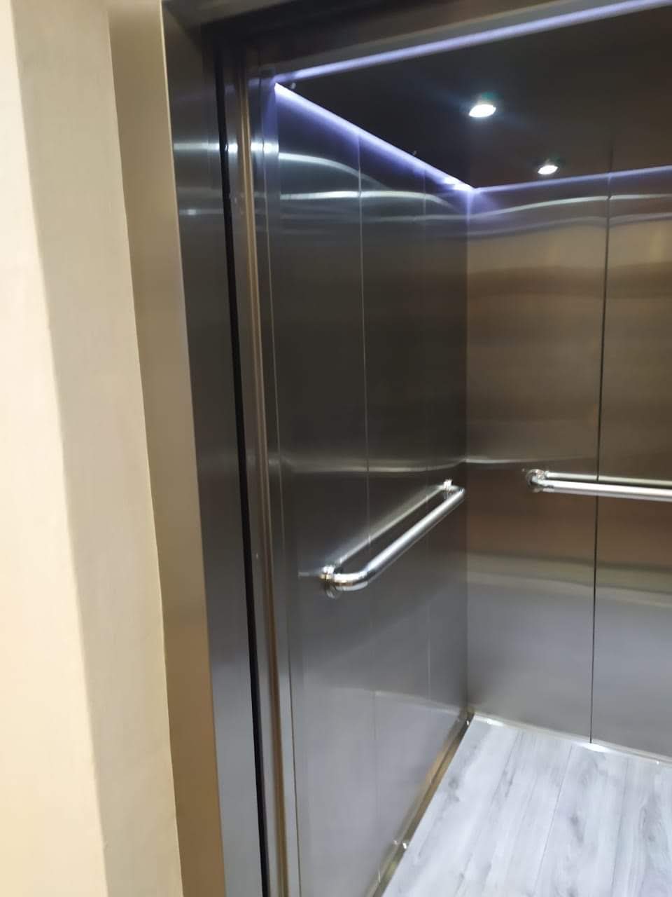 Interior de cabina de elevador residencial EPCCSA en acero inoxidable con iluminación LED y pasamanos